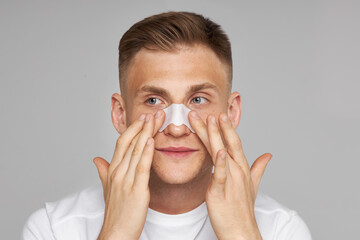 Beauty saloon. Facial skin care. Man applying white nose patch. Closeup of pore cleansing. Cleaning...