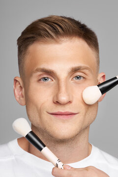 Men's makeup. Facial beauty treatments with cosmetics. Female hands with Touch Man's Face brushes with foundation.