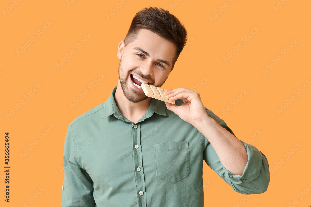 Sticker handsome young man with tasty chocolate on color background