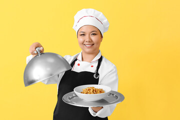 Beautiful Asian chef with dish on color background