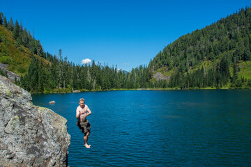 Adventurous male hiker jumping into an alpine lake in Washington State.