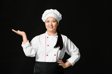 Beautiful Asian chef showing something on dark background