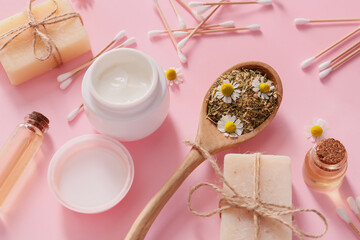 Cosmetics with chamomile flowers on color background