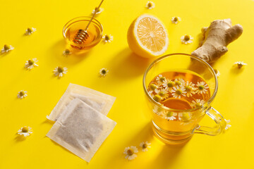Chamomile tea with honey, lemon and ginger on color background