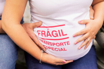 A couple holding a belly of pregnant woman with a print Fragile, special transport