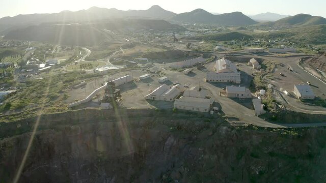 Aerial shot of buildings in city against mountains, drone descending forward towards city on sunny day - Bisbee, Arizona