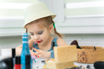 little girl a preschooler in a blue dress does makeup mom's makeup