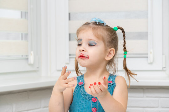 little girl put on funny mother's makeup and does manicure
