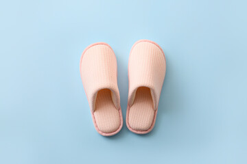 Pair of soft slippers on color background