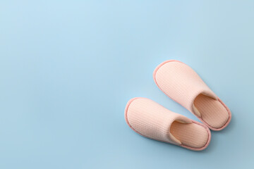 Pair of soft slippers on color background