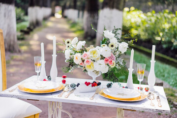 Wedding table serving with central flower, plates, berries in the woods
