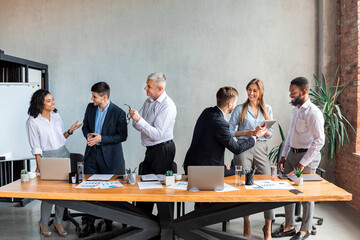 Coworkers Communicating Standing During Business Meeting In Modern Office