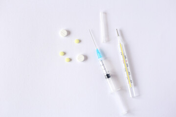 syringe, thermometer and pills on light background