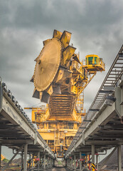 Huge Coal mining machinery on elevated tracks with a cloudy sky backdrop. 