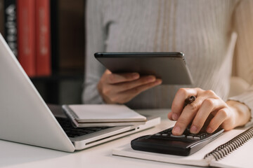 Finance accounting concept. Businesswoman working with tablet and using a calculator to calculate...