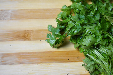 fresh coriander leafs on wood chopping board for vegetable cooking 