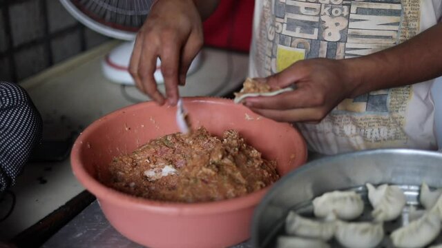 Stuffing raw Indian momo bread with minced chicken keema.