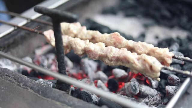 Roasting cooking chicken malai tikka on an Indian charcoal grill at a street food restaurant.
