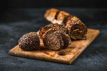 Rye baguette on cutting board. Pieces of pumpernickel brown bread closeup