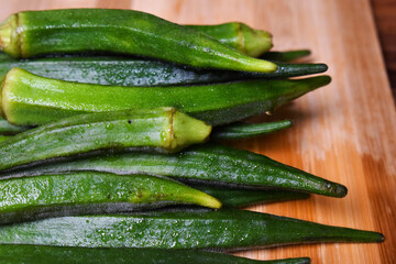 fresh lady fingers or okra vegetables on wooden chopping board