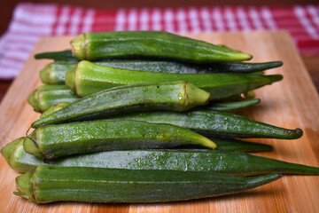 fresh lady fingers or okra vegetables on wooden chopping board