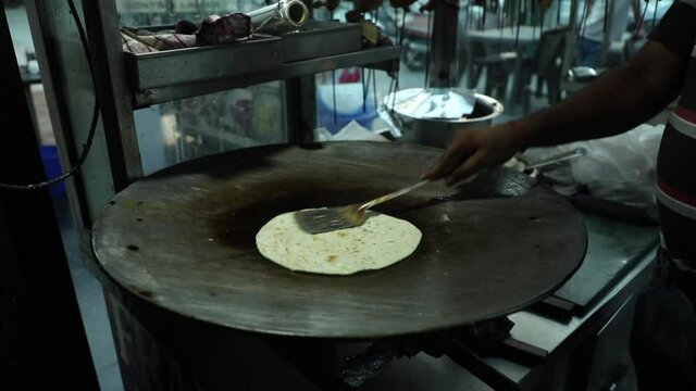 Cooking Indian bread parantha on a huge Indian pan at a street food restaurant. 