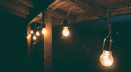 Fototapeta na wymiar The garland of light bulbs hanging on the wooden terrace