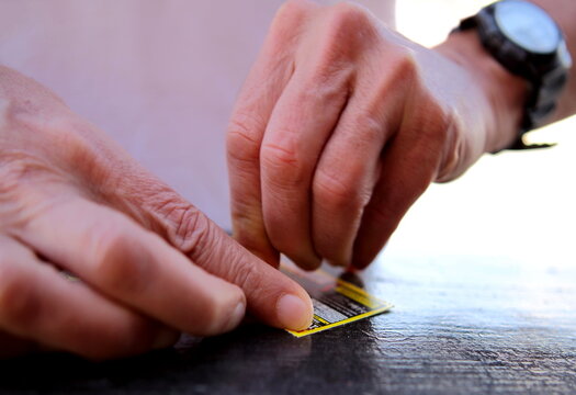 Photo of two hands scratching a scratch card with shallow focus.