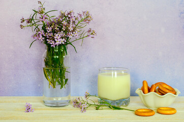 Rustic still life bagels a glass of milk and lilac wildflowers. Spring mood