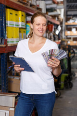 Woman  standing near racks in build store holding notebook and samples