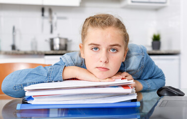 Tired girl sitting  among notebooks