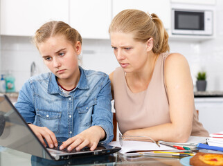 Strict woman supervising study of her daughter