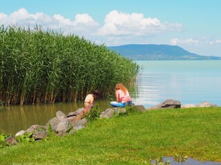 Balatonmáriafürdő, Hungary - June 06, 2020: Two young girls sitting on the stones on the...