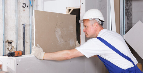 Worker engaged in drywall mounting