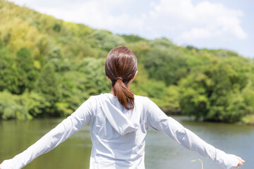 女性の一人旅、新緑を背景に女性の後ろ姿