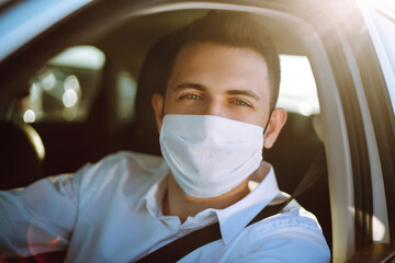 Fototapeta na wymiar Man driving a car puts on a medical mask during an epidemic in quarantine city. Health protection, safety and pandemic concept. Covid- 19.