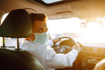 Man driving a car puts on a medical mask during an epidemic in quarantine city. Health protection, safety and pandemic concept. Covid- 19.