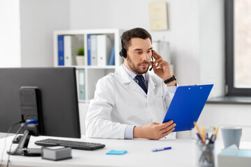 healthcare, medicine and technology concept - male doctor with headset and clipboard working at...