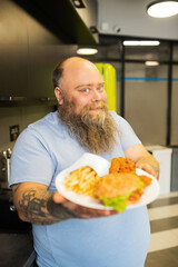 Smiling bearded man holding a plate of food forward