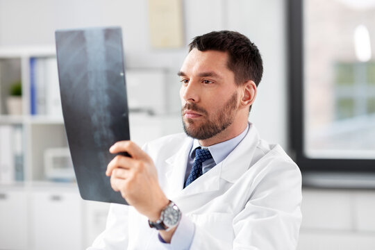 healthcare, medicine and people concept - male doctor with x-ray of spine at hospital