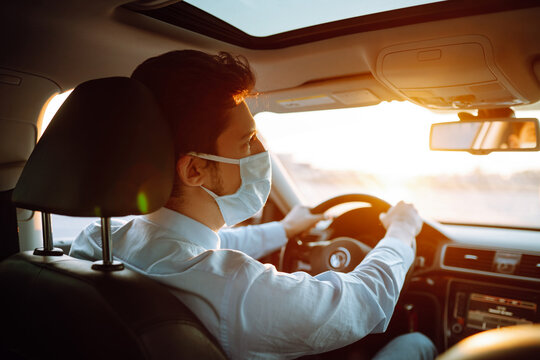 Young man  in protective sterile medical mask sits in the car during an epidemic in quarantine city. Health protection, safety and pandemic concept. Covid - 19.