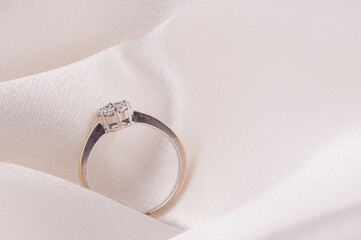 Wedding rings/ Engagement ring with diamonds isolated over white satin cloth