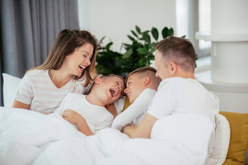 Obraz premium Young family enjoying at home. Happy parents with sons relaxing on sofa. 