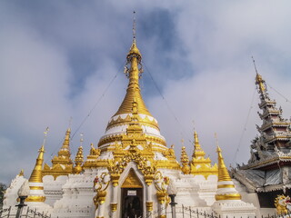 Naklejka premium view morning of Golden Pagoda around with soft mist and blue sky background, Wat Chong Kham, Mae Hong Son, northern of Thailand.