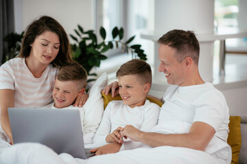 Young family watching movie on lap top. Beautiful parents with kids enjoying at home.	