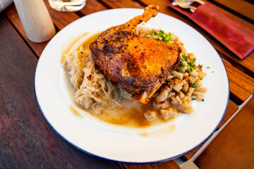 Baked duck leg with stewed cabbage and small gnocchi on plate.