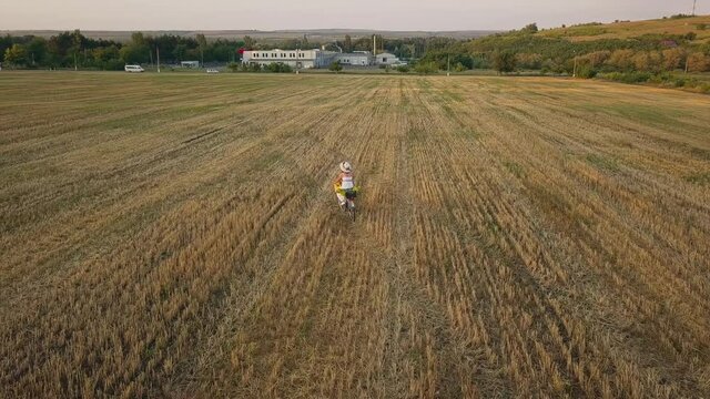 Top view of a woman in a white dress leading a bicycle on a field with sunflowers. Drone futage 4K.