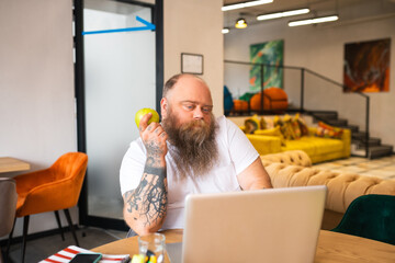 Bald bearded man in white tshirt watching something online