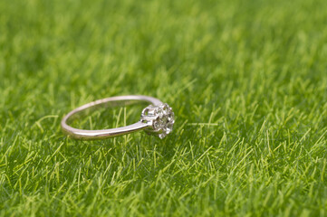 A single female wedding ring with diamond isolated over green grass