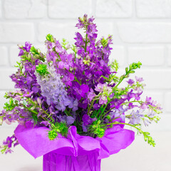 Beautiful bouquet of lilac purple flowers in a vase on a white background. Mother's day. Greeting card. Place for an inscription.